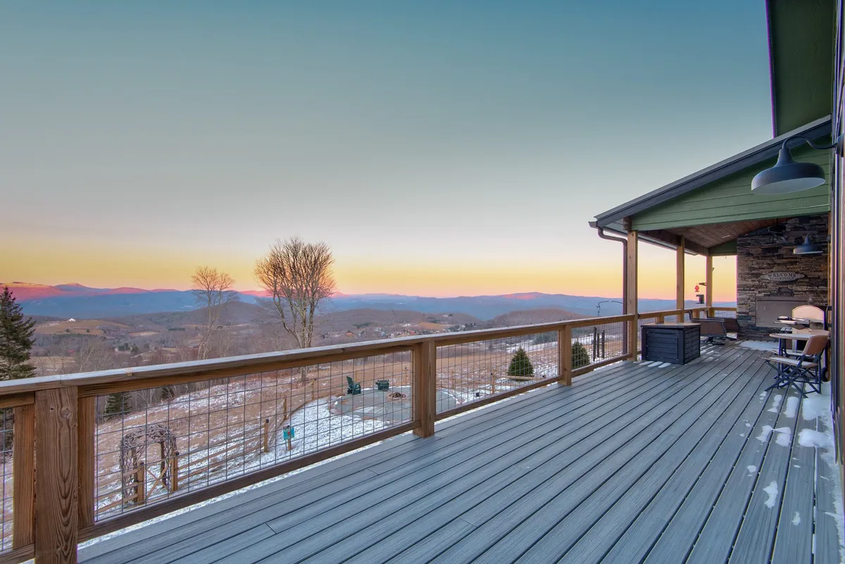 This image captures an expansive deck with comfortable seating, set against a breathtaking mountain backdrop and a sky painted with sunset hues. The tranquil atmosphere invites relaxation, outdoor dining, and stargazing, echoing the retreat's promise of scenic luxury and memorable gatherings.