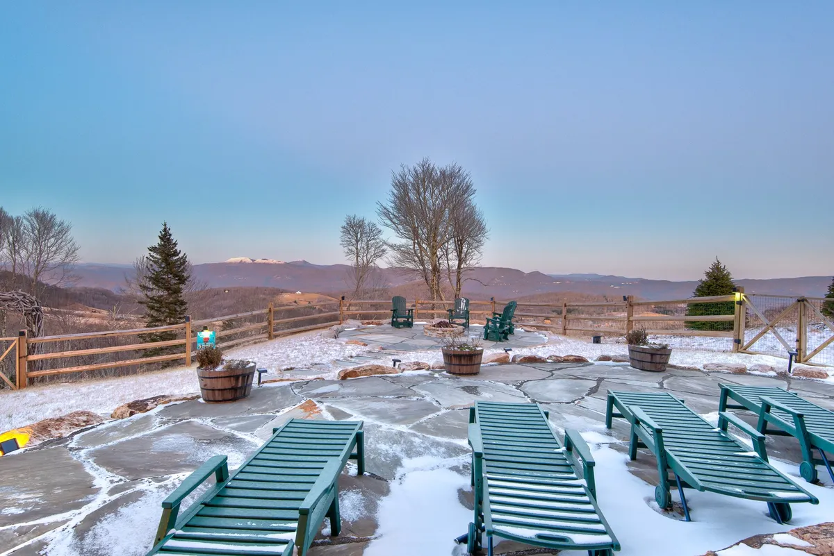 A tranquil fenced backyard with lounge chairs facing mountain views, trees, and a clear fence line. The space is ideal for relaxing, safe play for pets, or taking in the scenery.