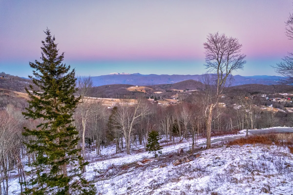 A sweeping view of a mountain range, tree line, and snowy ground. This inspiring vista encourages exploration of the local natural beauty and hints at the hiking and outdoor activities available just steps away from the property.